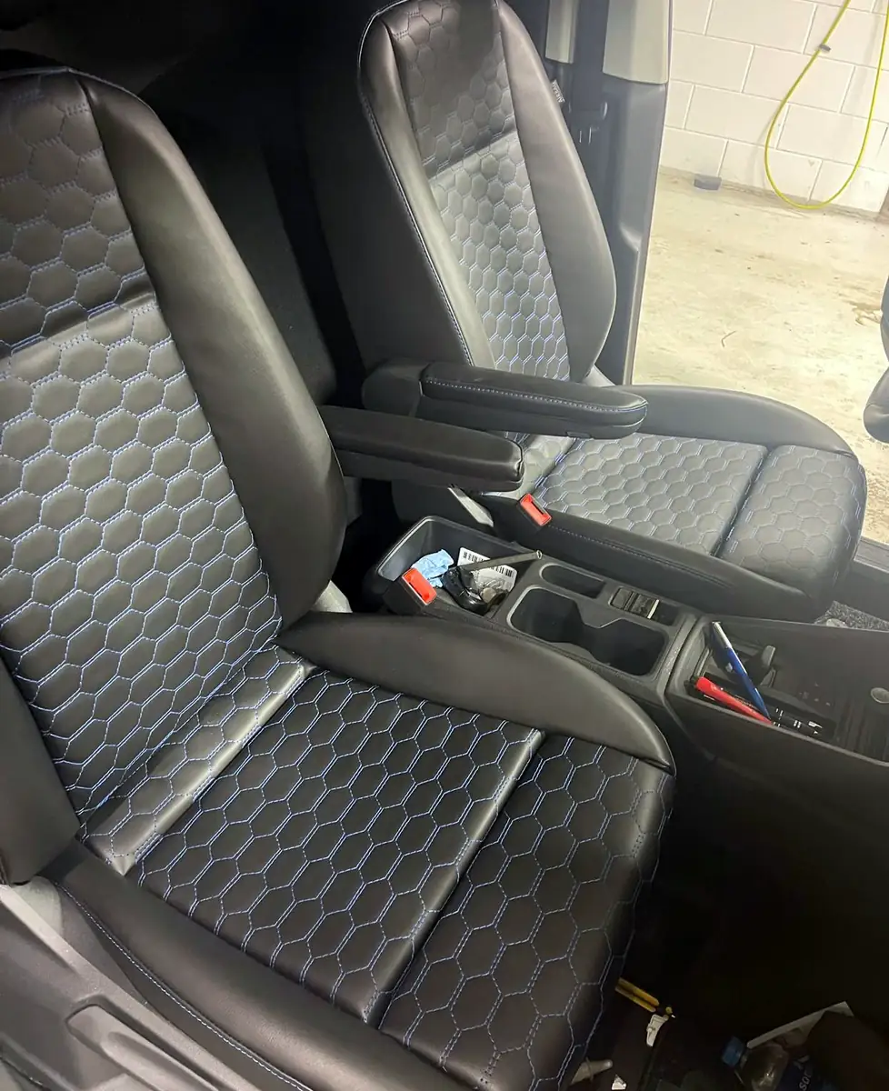 Voorstoelen van een auto in zwart leer met een honingraatstiksel op zitting en rug, ingebouwd in de auto.